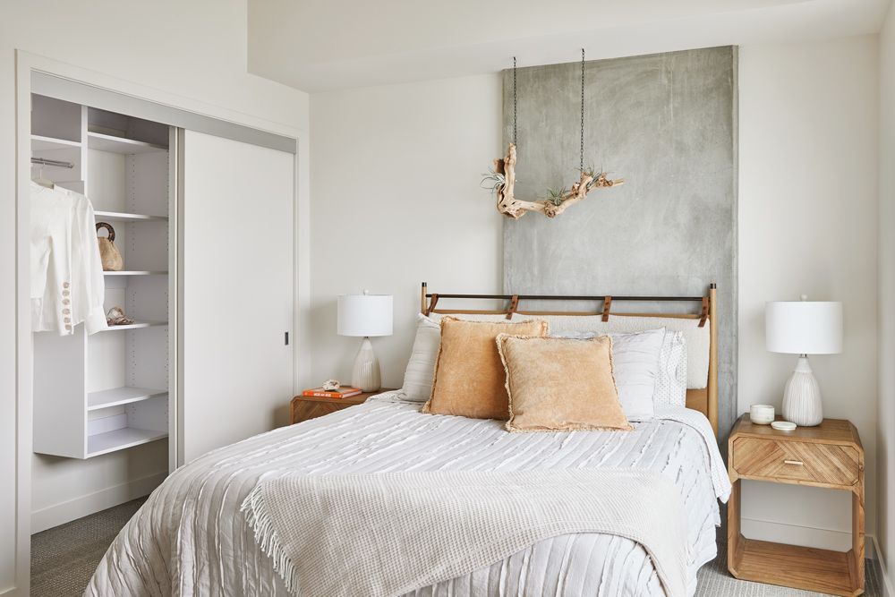 Bright bedroom with white bedding, wood nightstands, and open closet doors