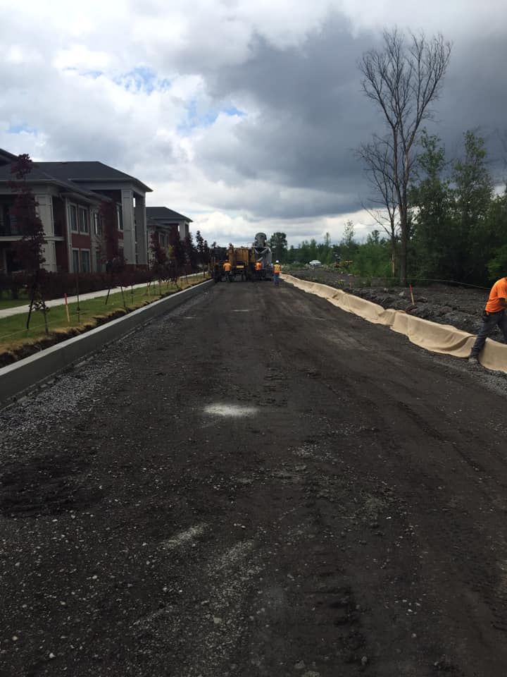 Un homme se tient au bord d’une route avec un bulldozer en arrière-plan.