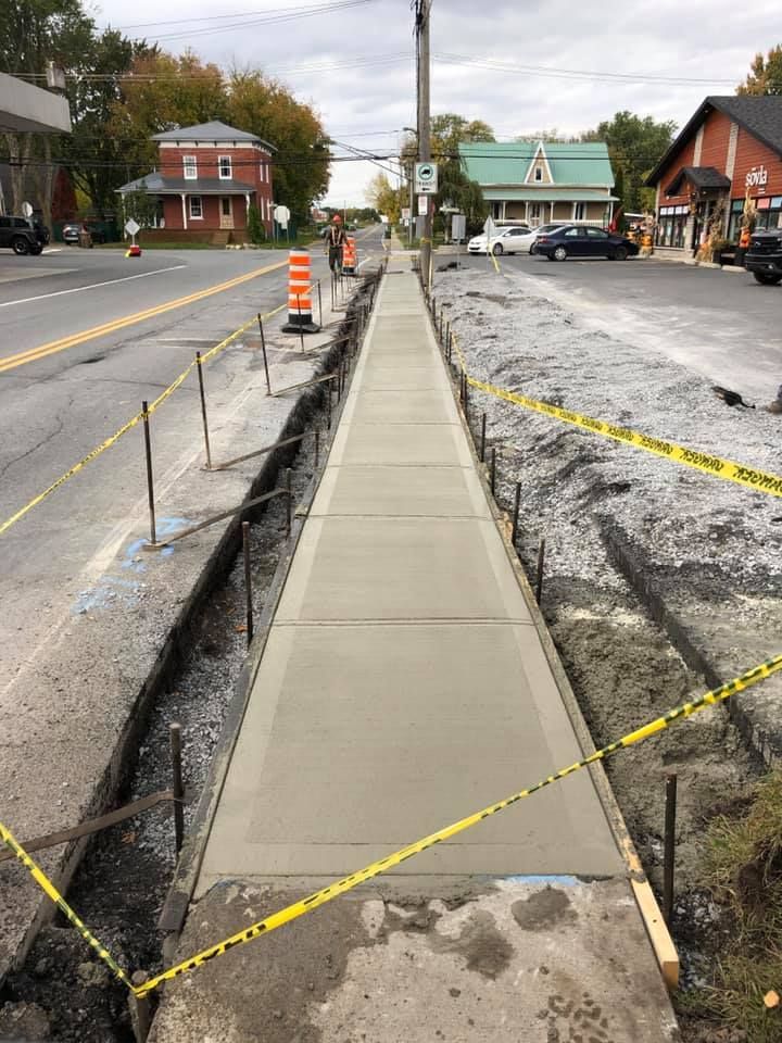 Un trottoir est en cours de construction au bord d'une route.