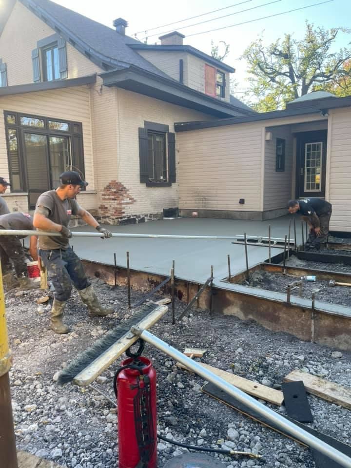 Un groupe d’hommes travaille sur une terrasse en béton devant une maison.