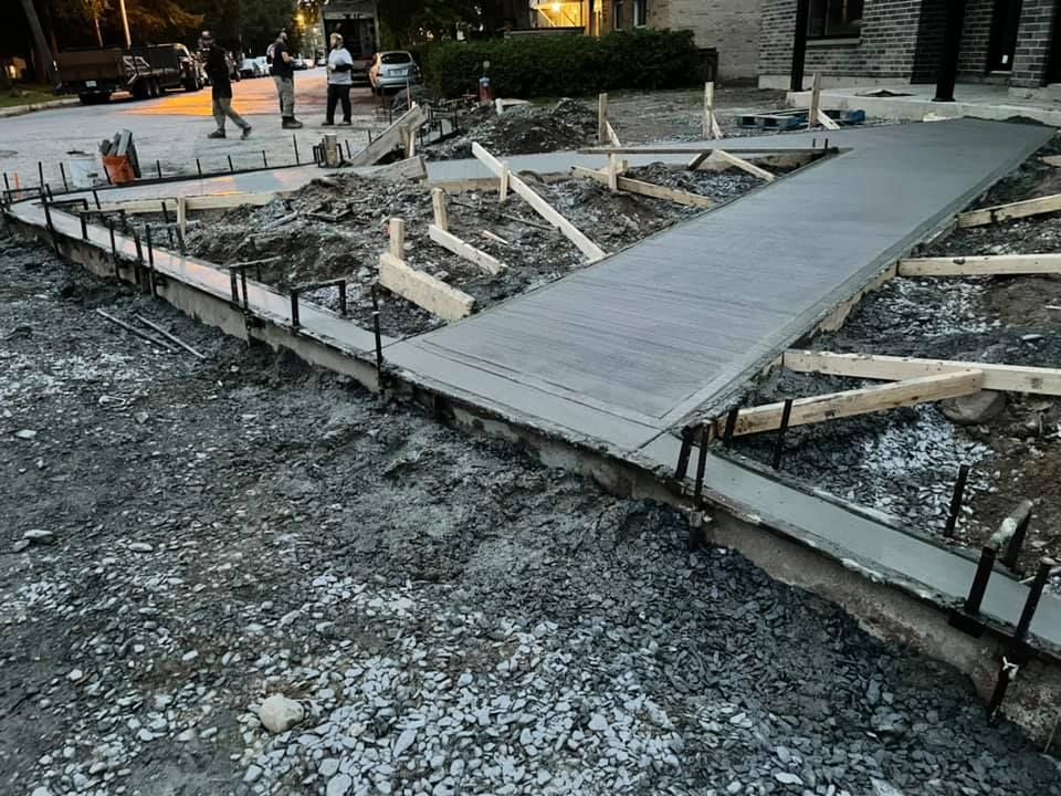 Une passerelle en béton est en cours de construction devant une maison.