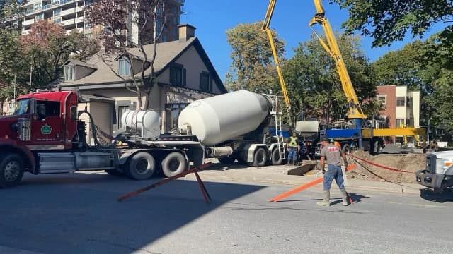 Un homme marche devant un camion malaxeur à béton.