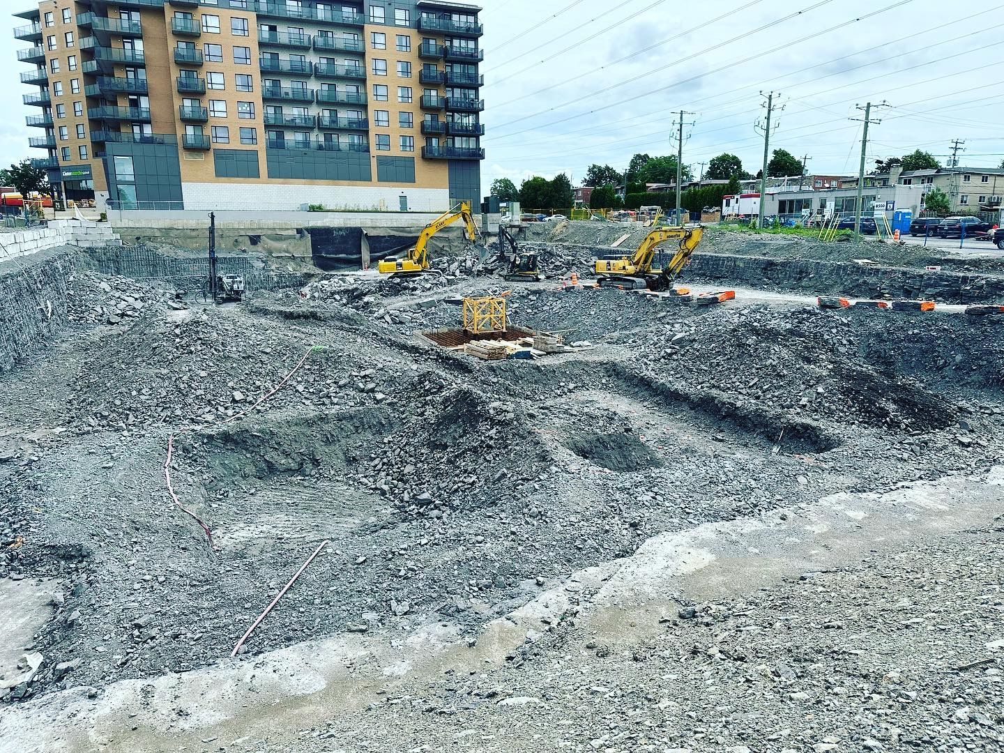 Un chantier de construction avec beaucoup de gravier et un bâtiment en arrière-plan.