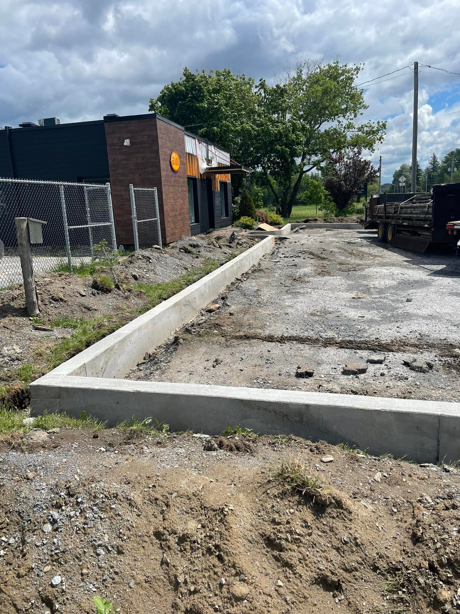 Un bâtiment en brique est en construction à côté d'un chemin de terre.