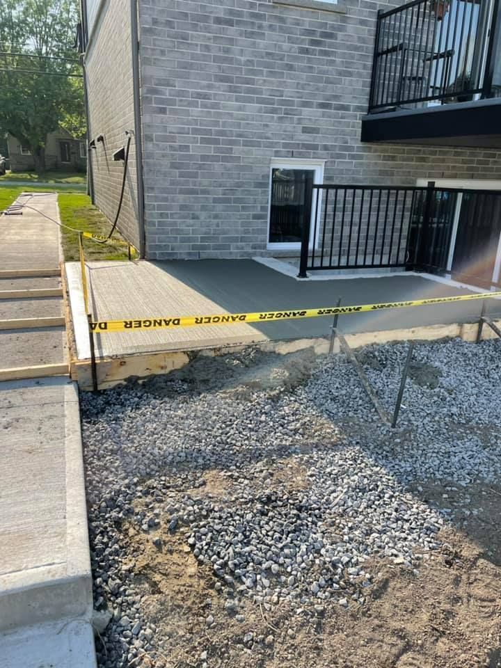 Une passerelle en béton est en cours de construction devant un bâtiment en brique.