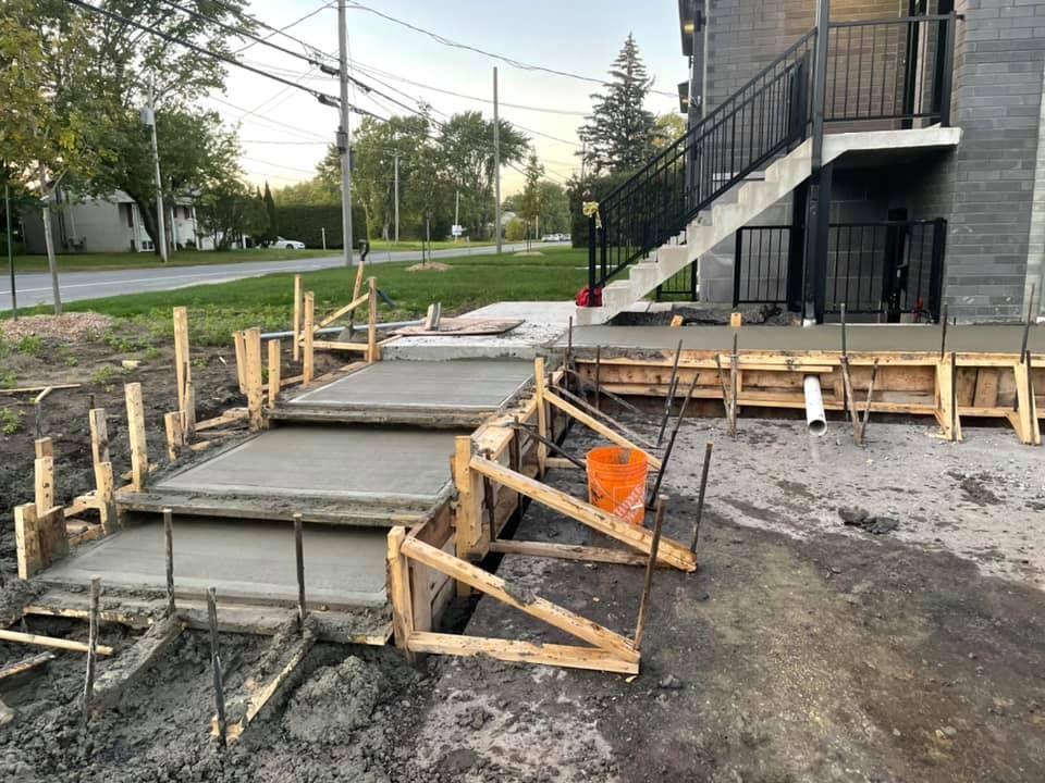 Une passerelle en béton est en cours de construction devant un immeuble.