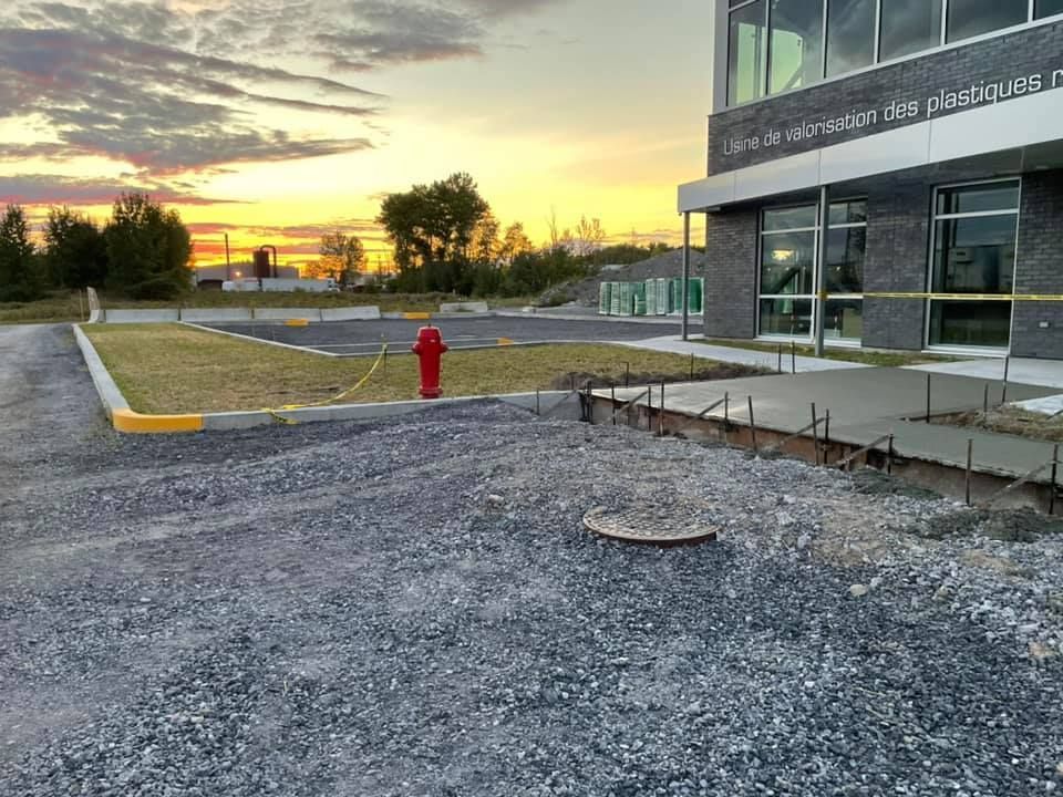 Une bouche d'incendie se trouve dans une zone de gravier devant un bâtiment.