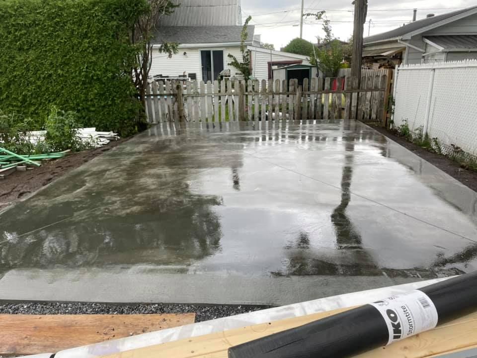 Une allée en béton est en cours de construction dans la cour d'une maison.