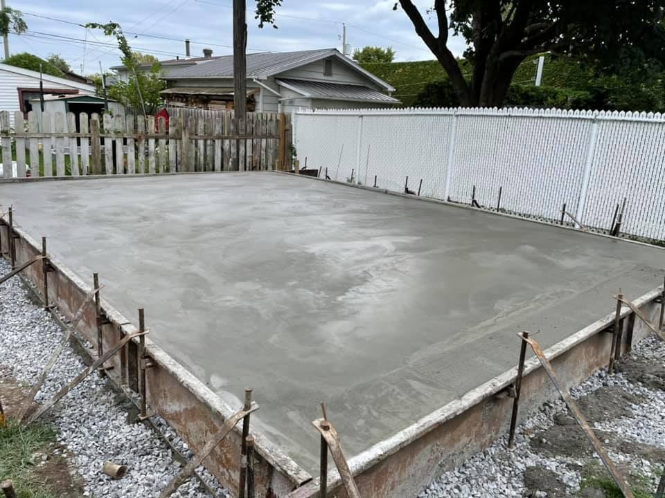 Une fondation en béton est en cours de construction devant une maison.
