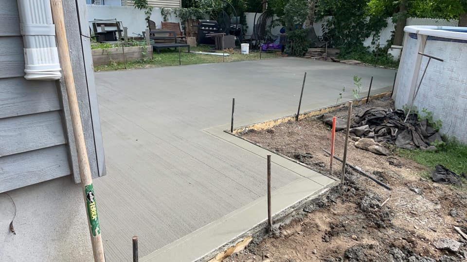 Une allée en béton est en cours de construction devant une maison.