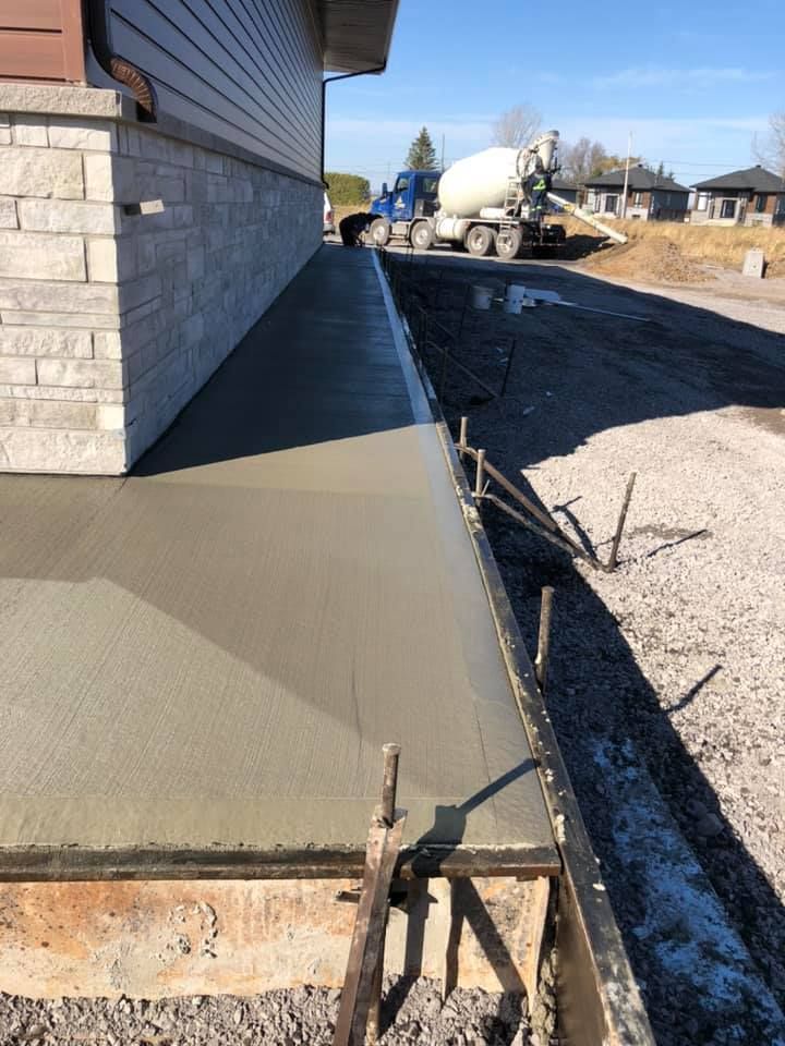 Un camion à béton coule du béton sur le côté d'une maison.