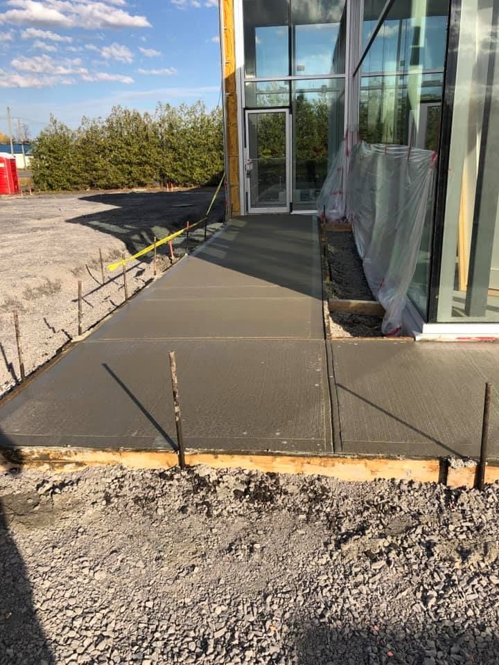 Une passerelle en béton est en cours de construction devant un immeuble.