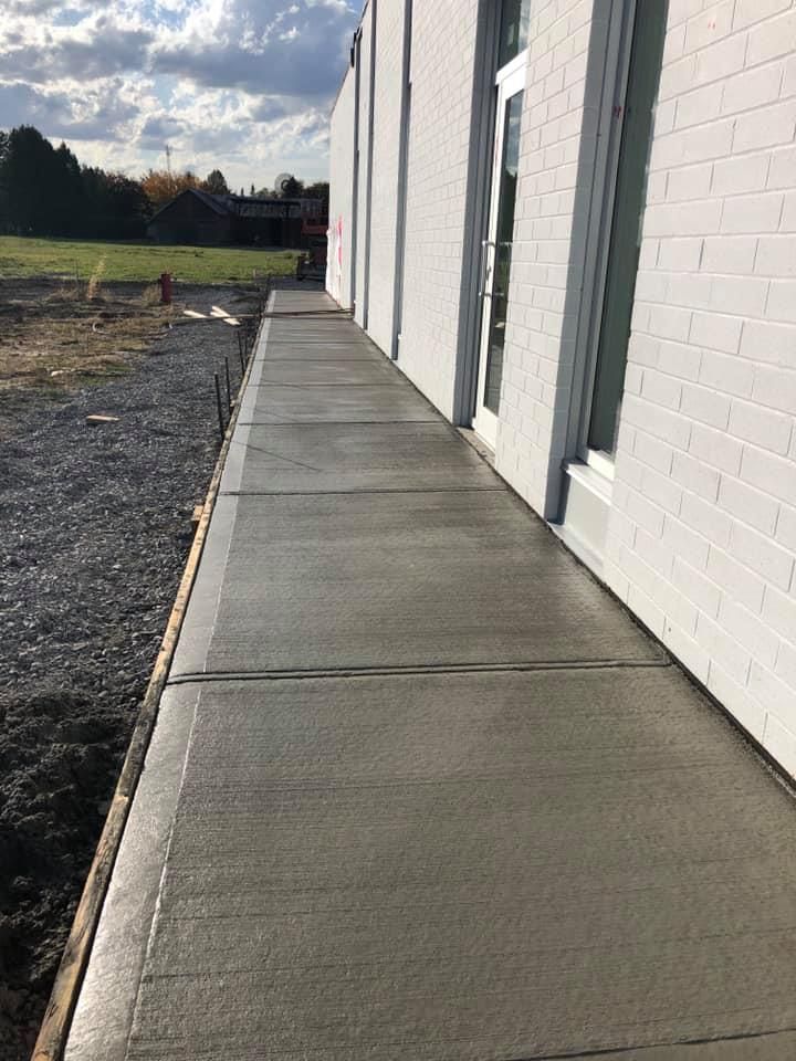 Un trottoir est en construction devant un immeuble en briques blanches.