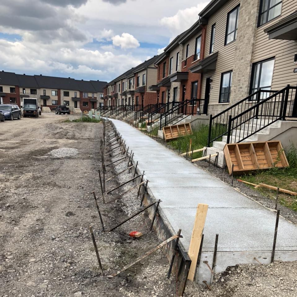 Un trottoir est en construction devant une rangée de maisons