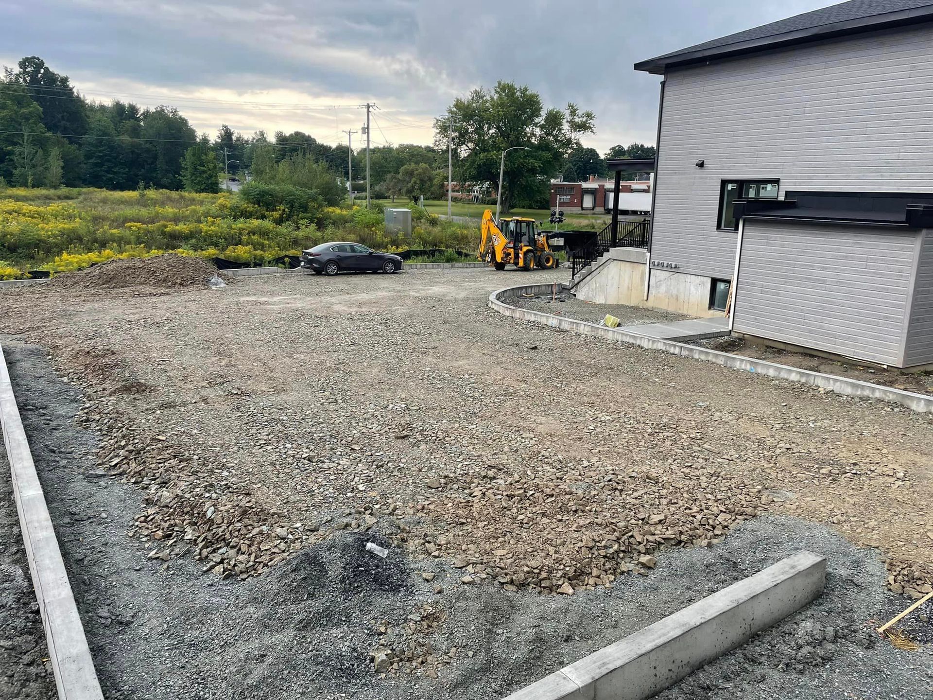 Un chantier de construction avec une maison en arrière-plan et une voiture garée devant.