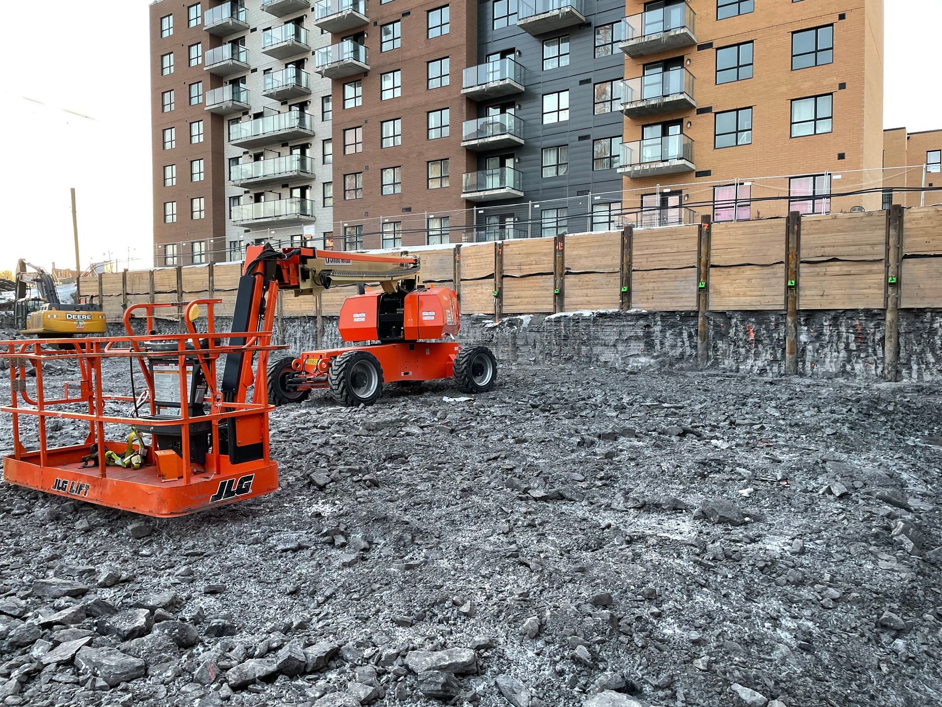 Un chantier de construction avec beaucoup de machines et un bâtiment en arrière-plan.