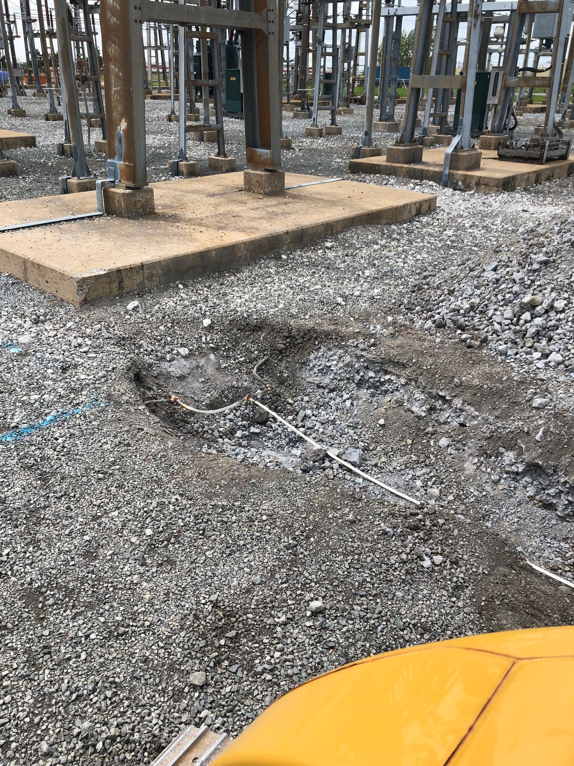Un véhicule jaune est garé dans une zone de gravier devant une centrale électrique.