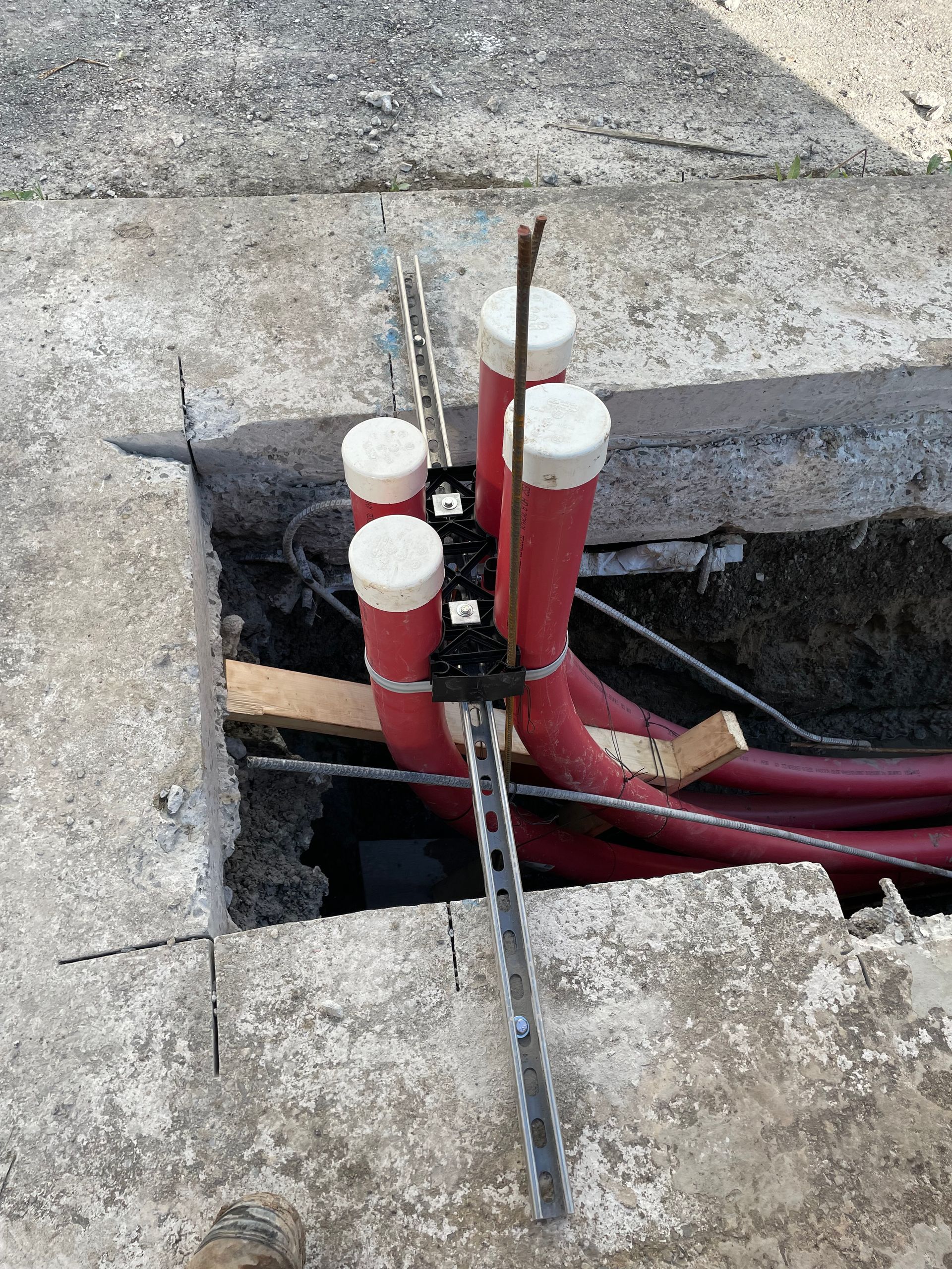 Un tas de tuyaux rouges sont posés dans un trou dans le sol.