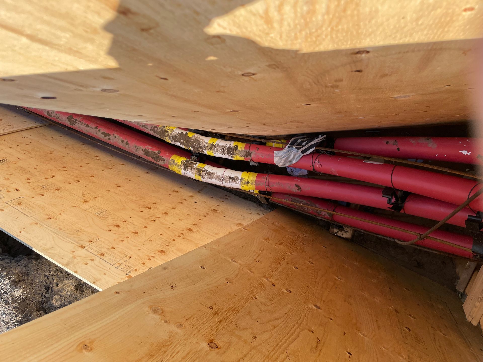 Un tas de tuyaux rouges sont posés sur un plancher en bois