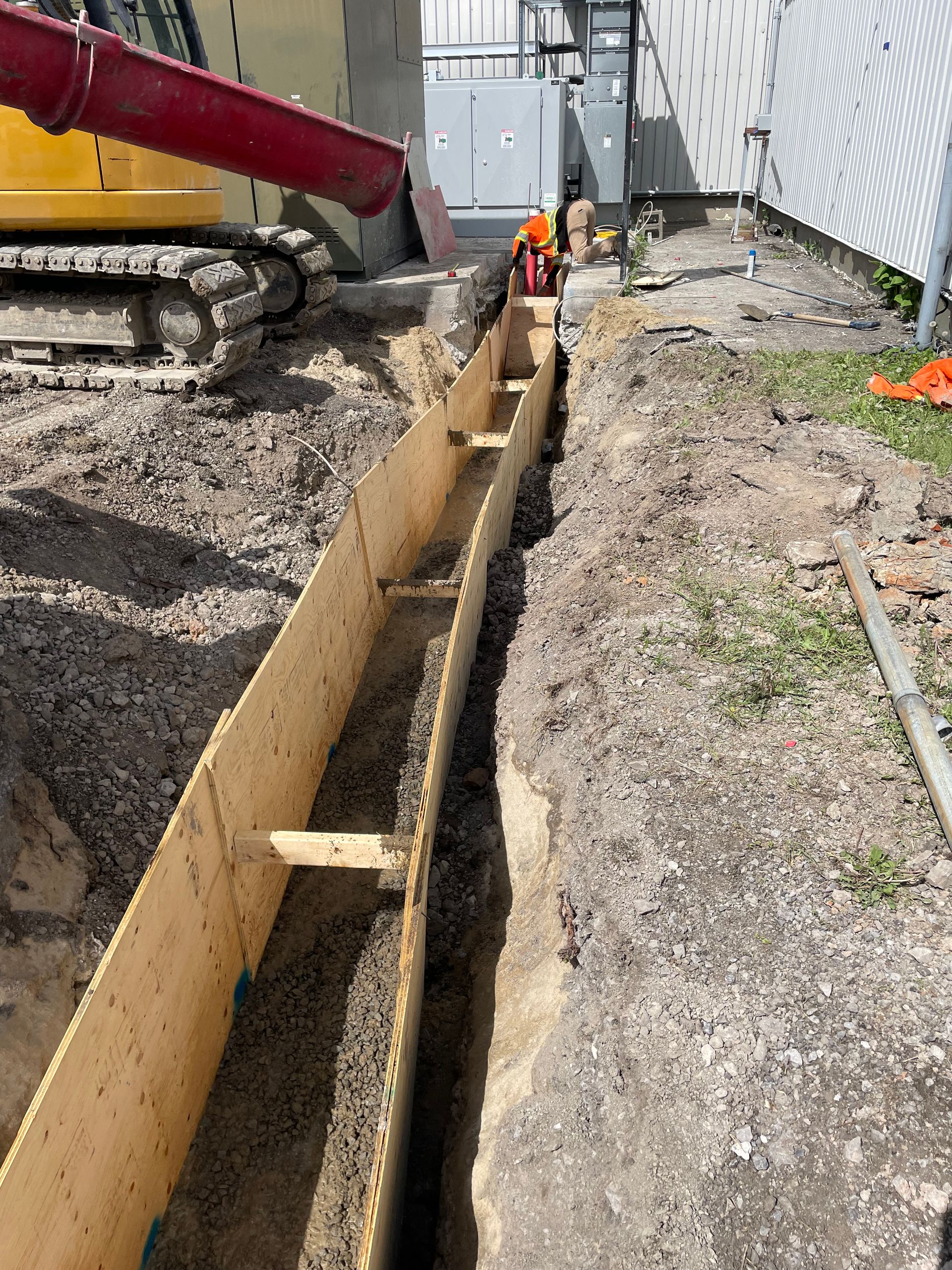 Un chantier de construction avec une grue versant du béton dans une tranchée.