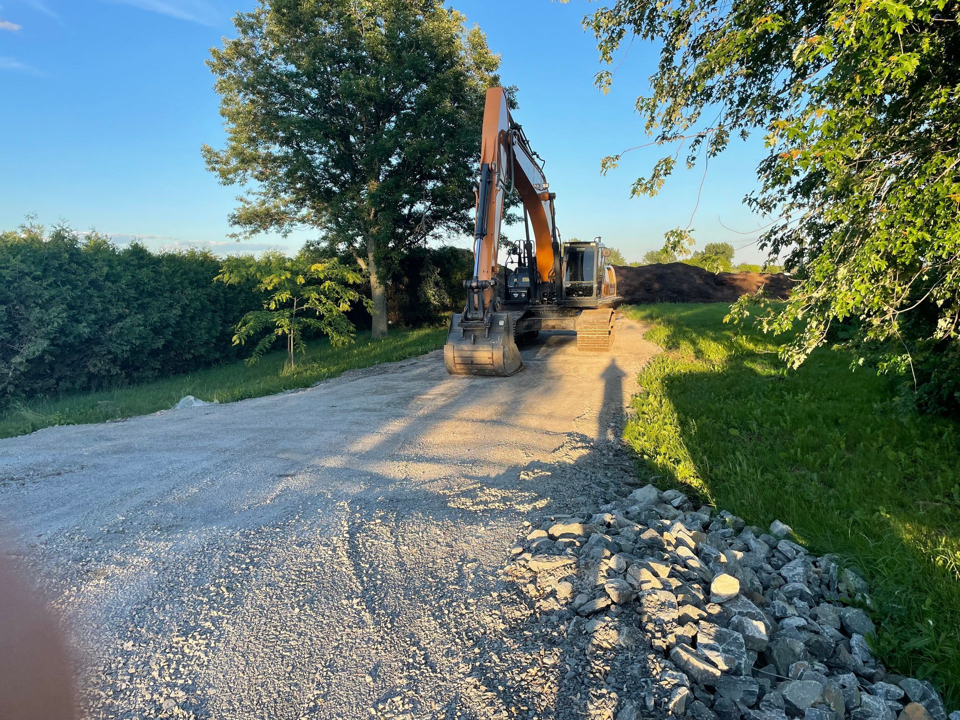 Une grosse excavatrice roule sur une route de gravier.