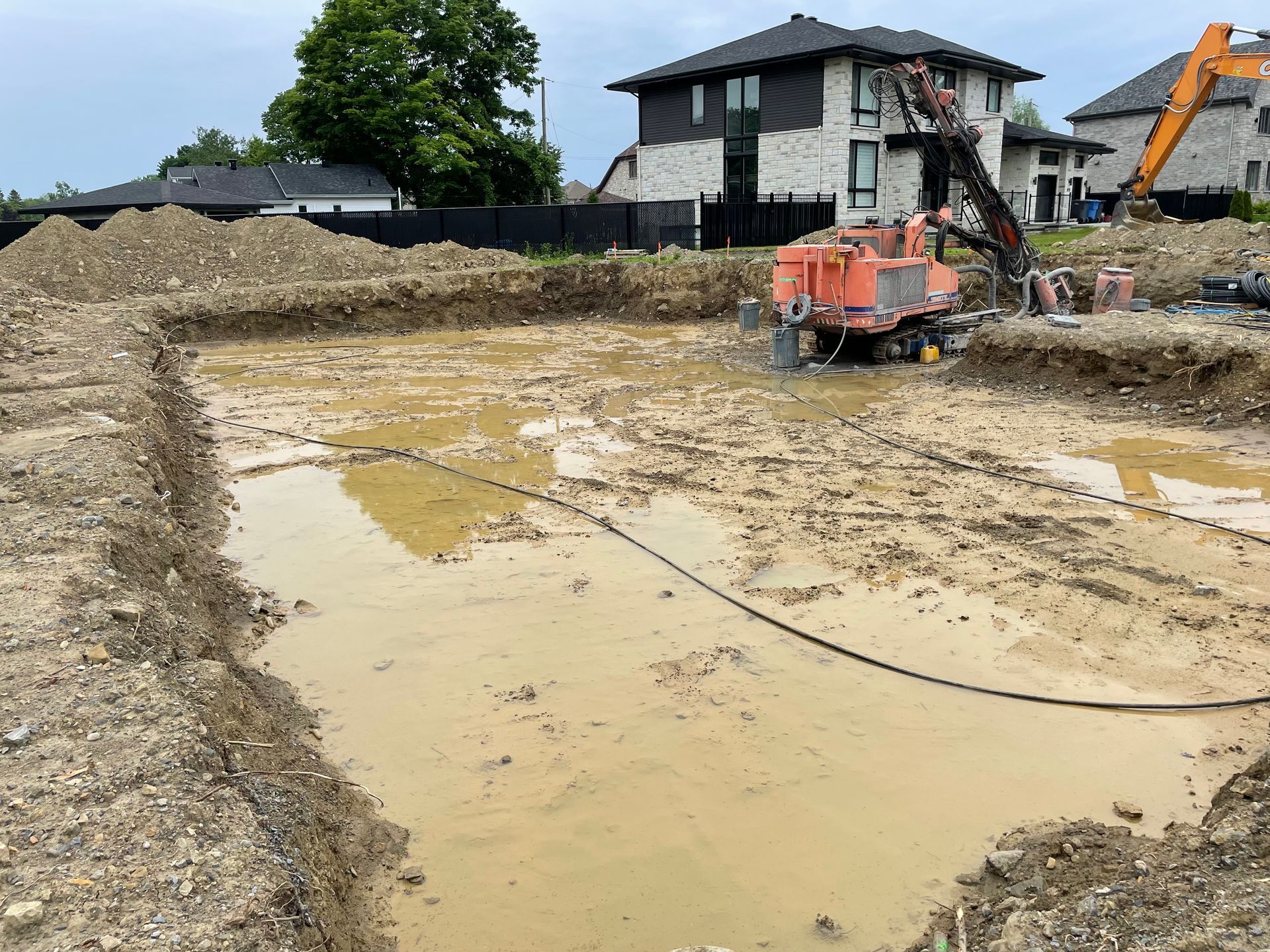 Un chantier de construction avec beaucoup de terre et une maison en arrière-plan.
