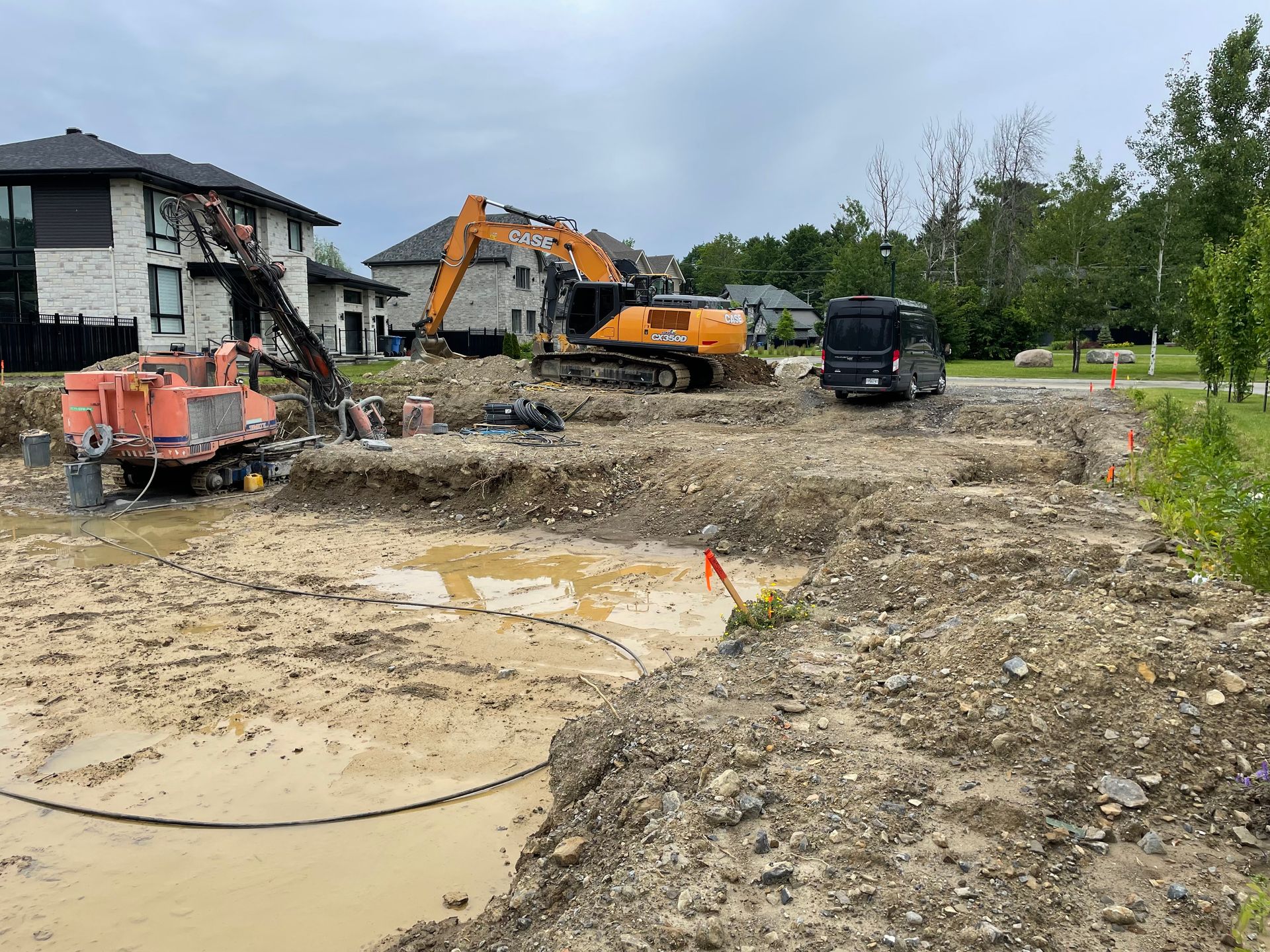 Un chantier de construction avec beaucoup de terre et une maison en arrière-plan.