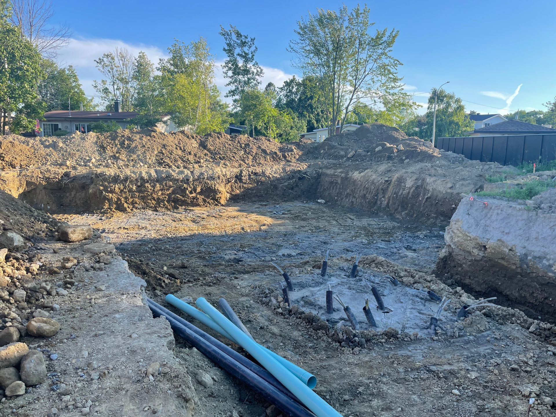 Un tas de tuyaux repose dans la terre sur un chantier de construction.