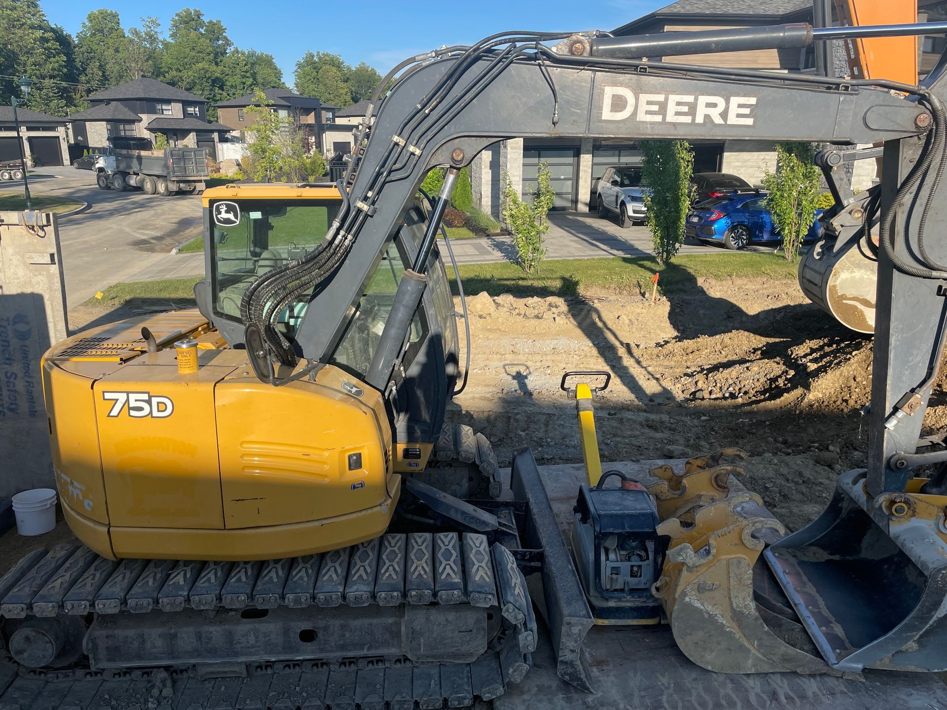 Une excavatrice Deere est garée devant une maison.