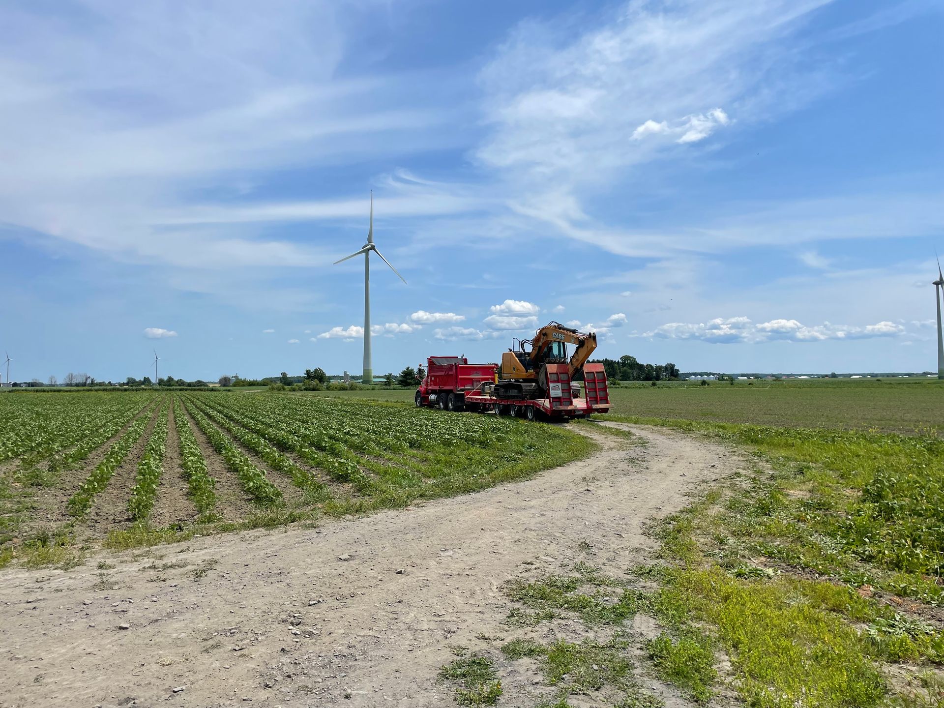 Un tracteur roule sur un chemin de terre dans un champ.