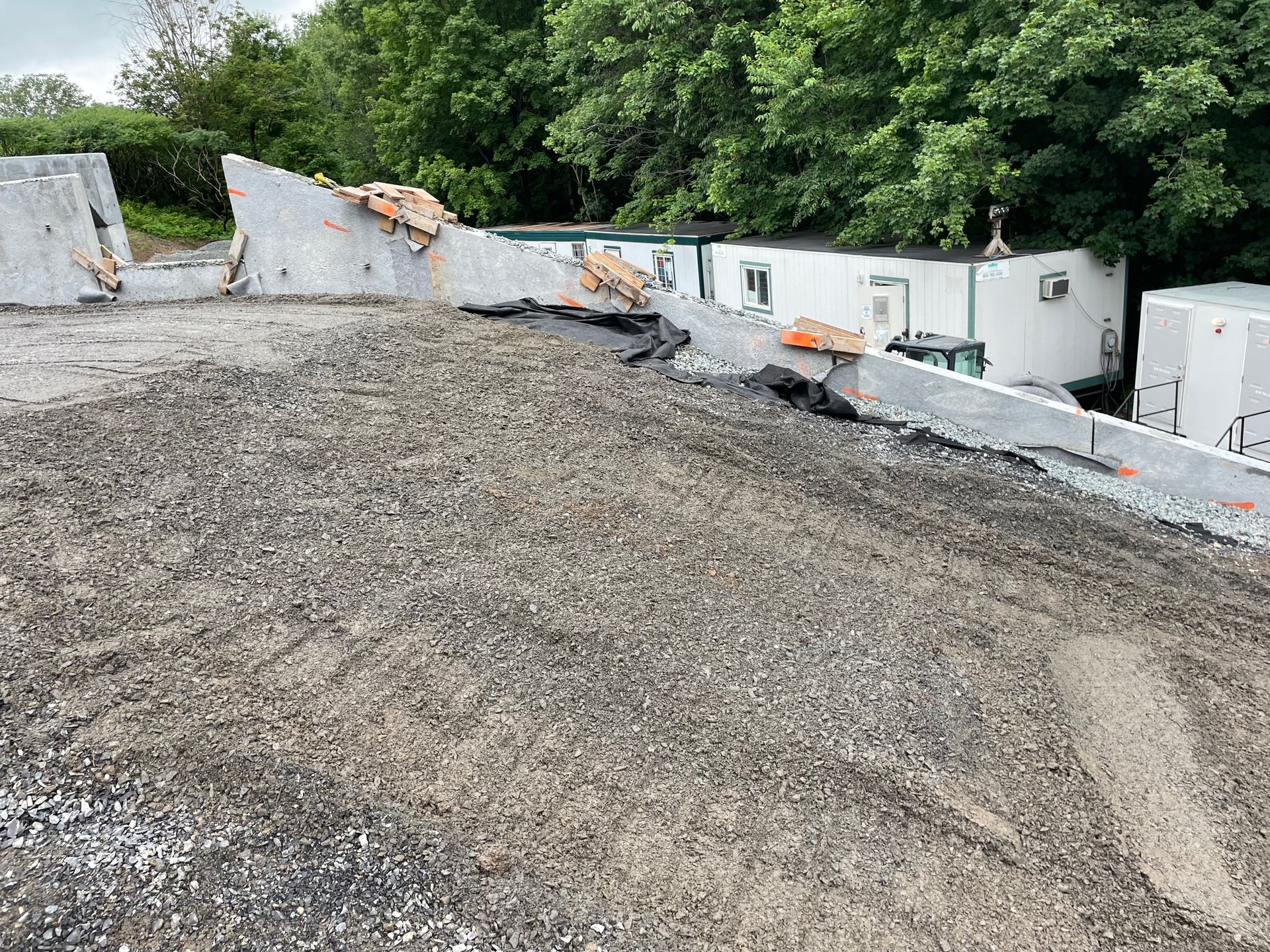 Un chantier de construction avec beaucoup de graviers et d'arbres en arrière-plan.