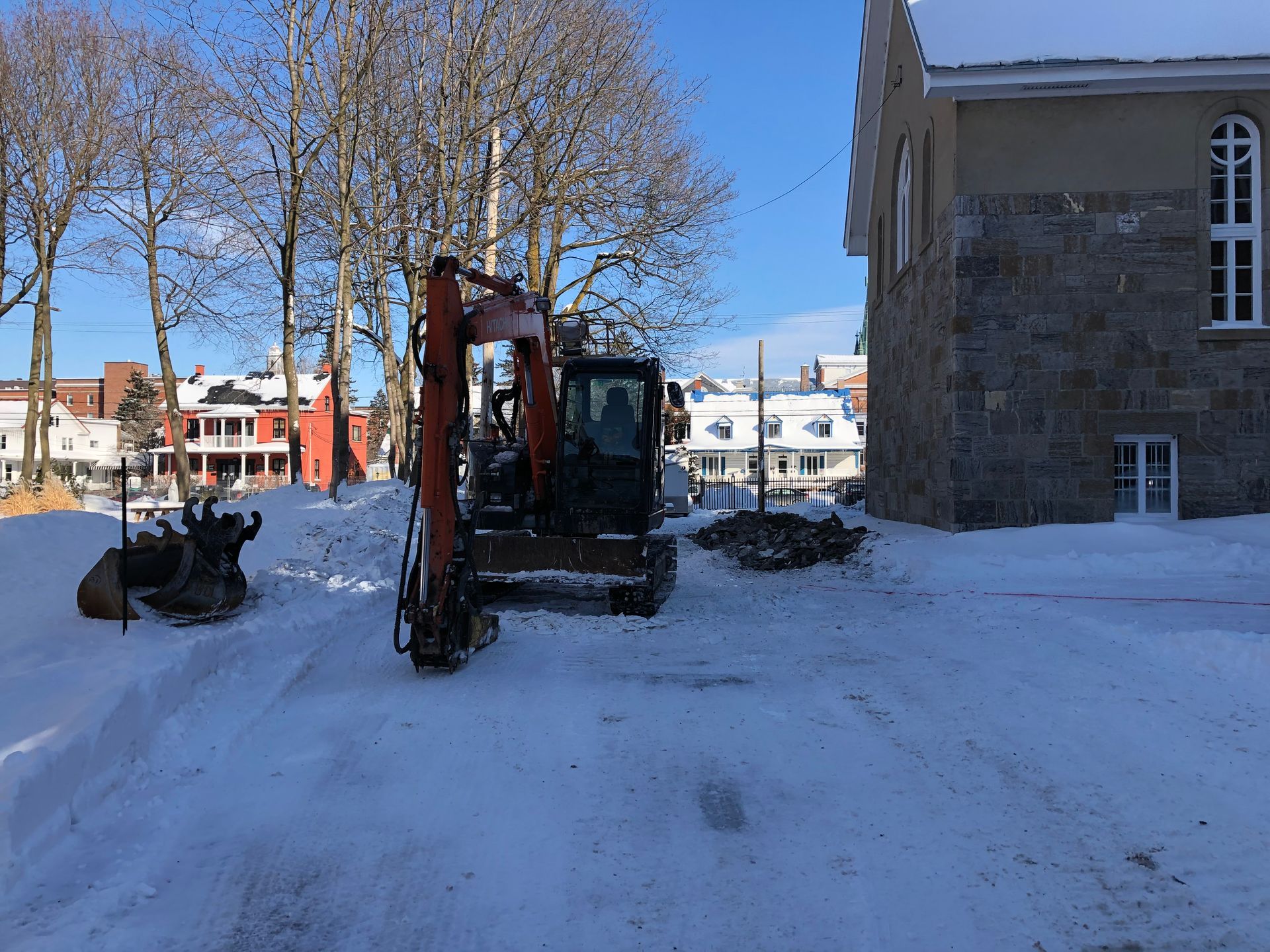 Une excavatrice est garée dans la neige devant un bâtiment
