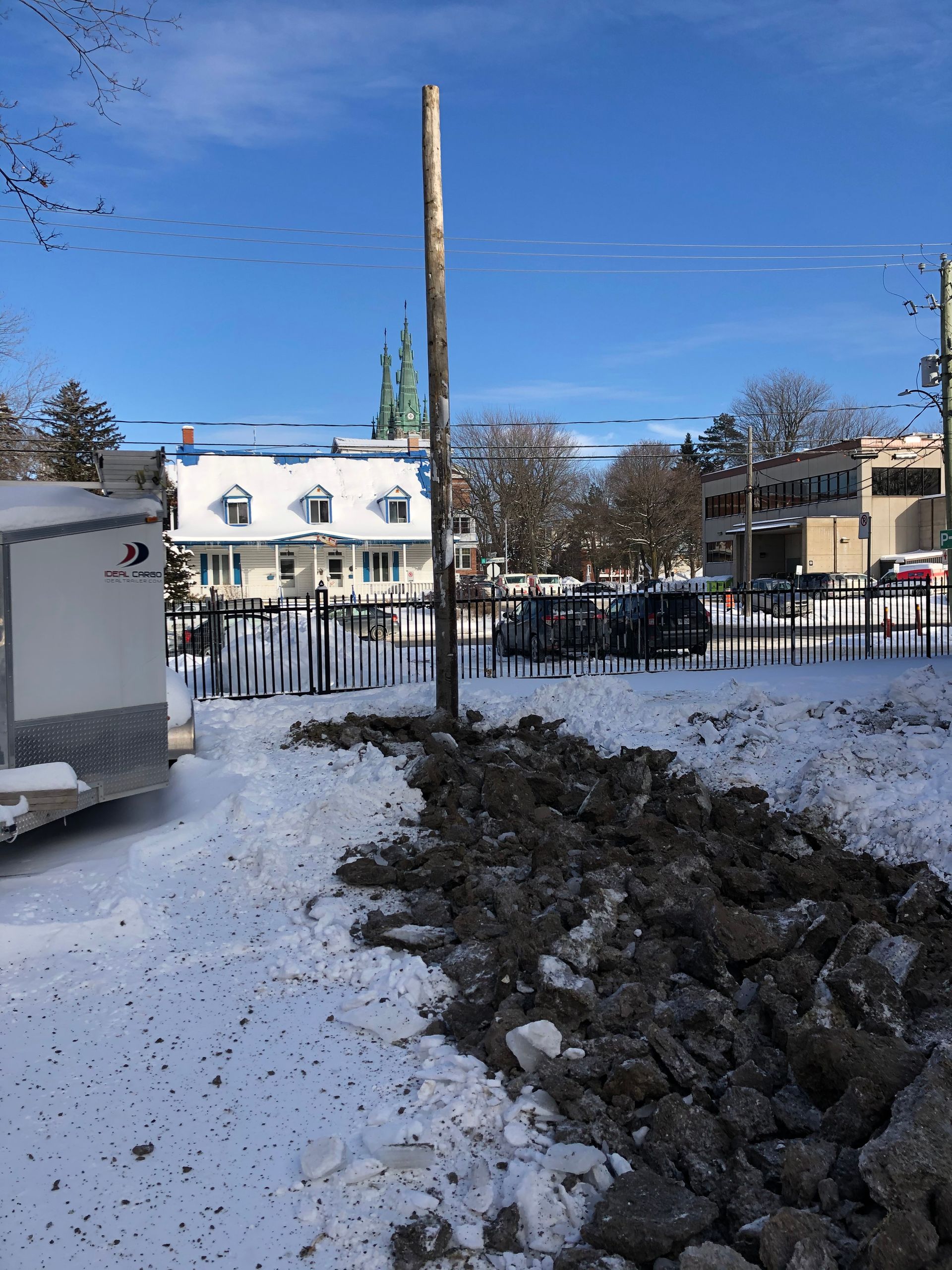 Une caravane blanche est garée dans la neige devant un immeuble.