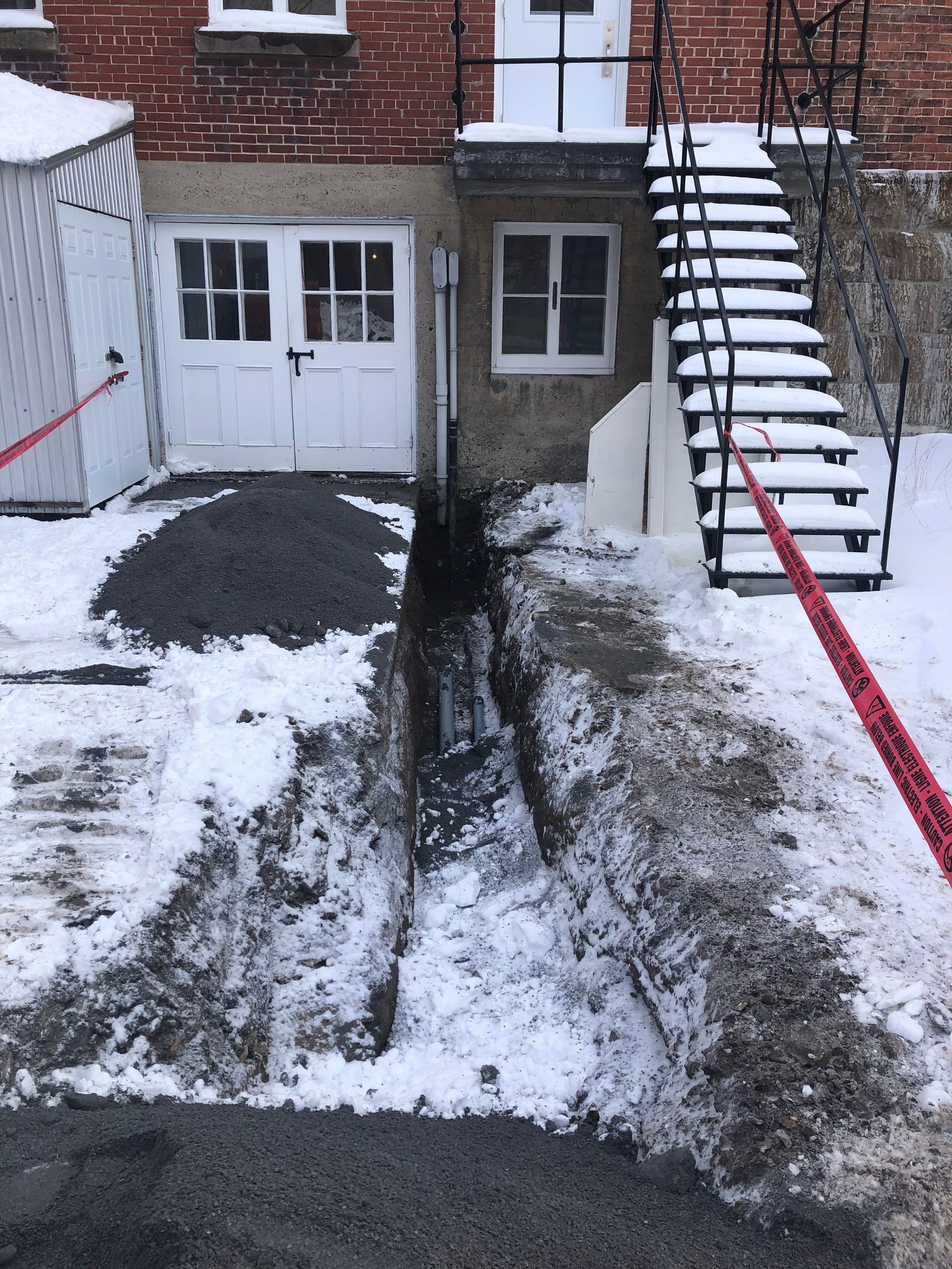 Un bâtiment en brique avec des escaliers qui y mènent est couvert de neige