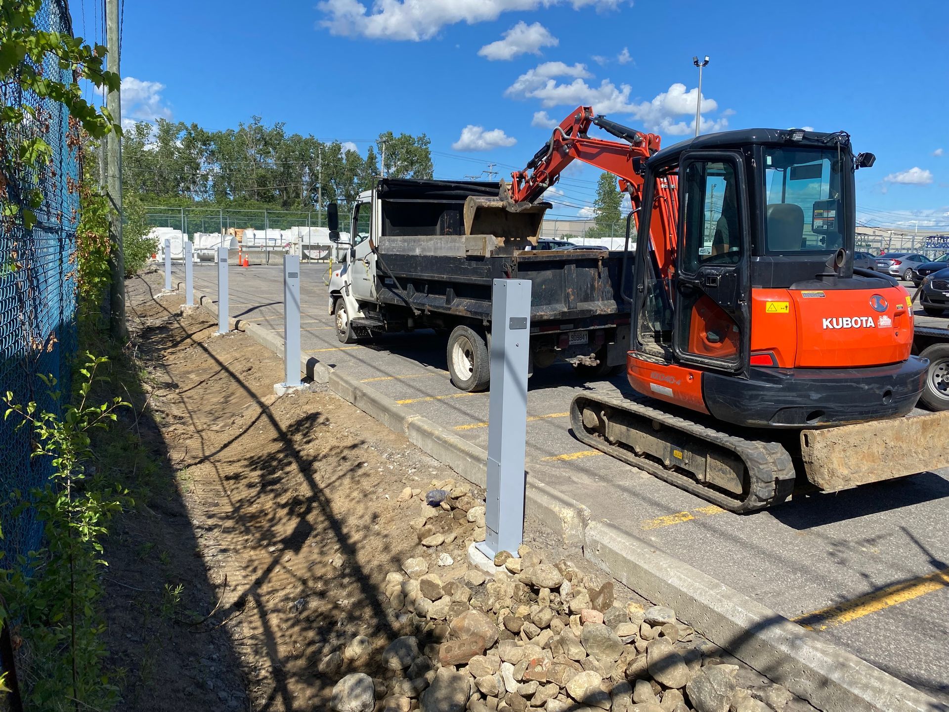 Une excavatrice charge de la terre dans un camion-benne dans un parking.