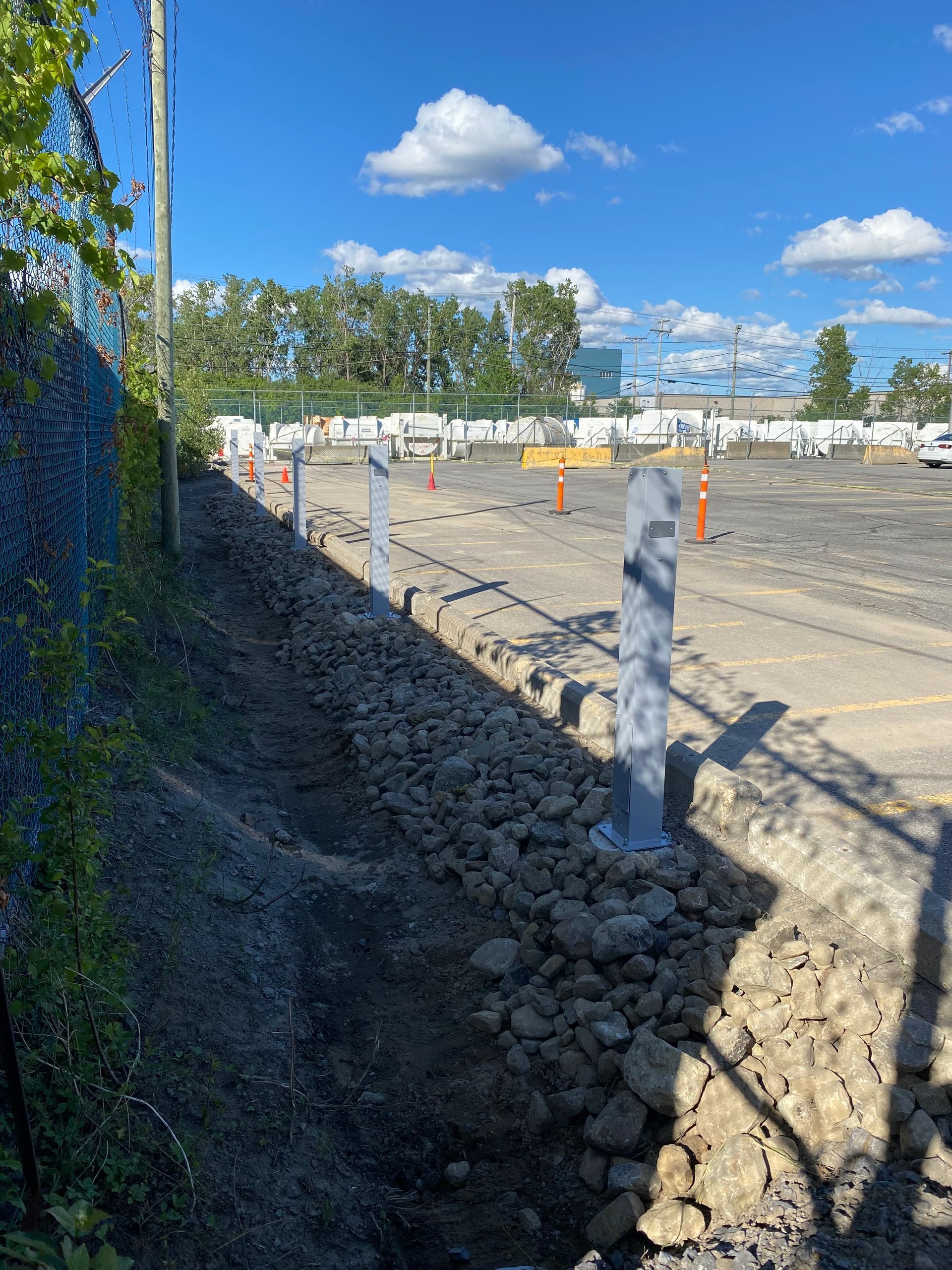 Un chantier de construction avec une clôture à mailles losangées et beaucoup de rochers.