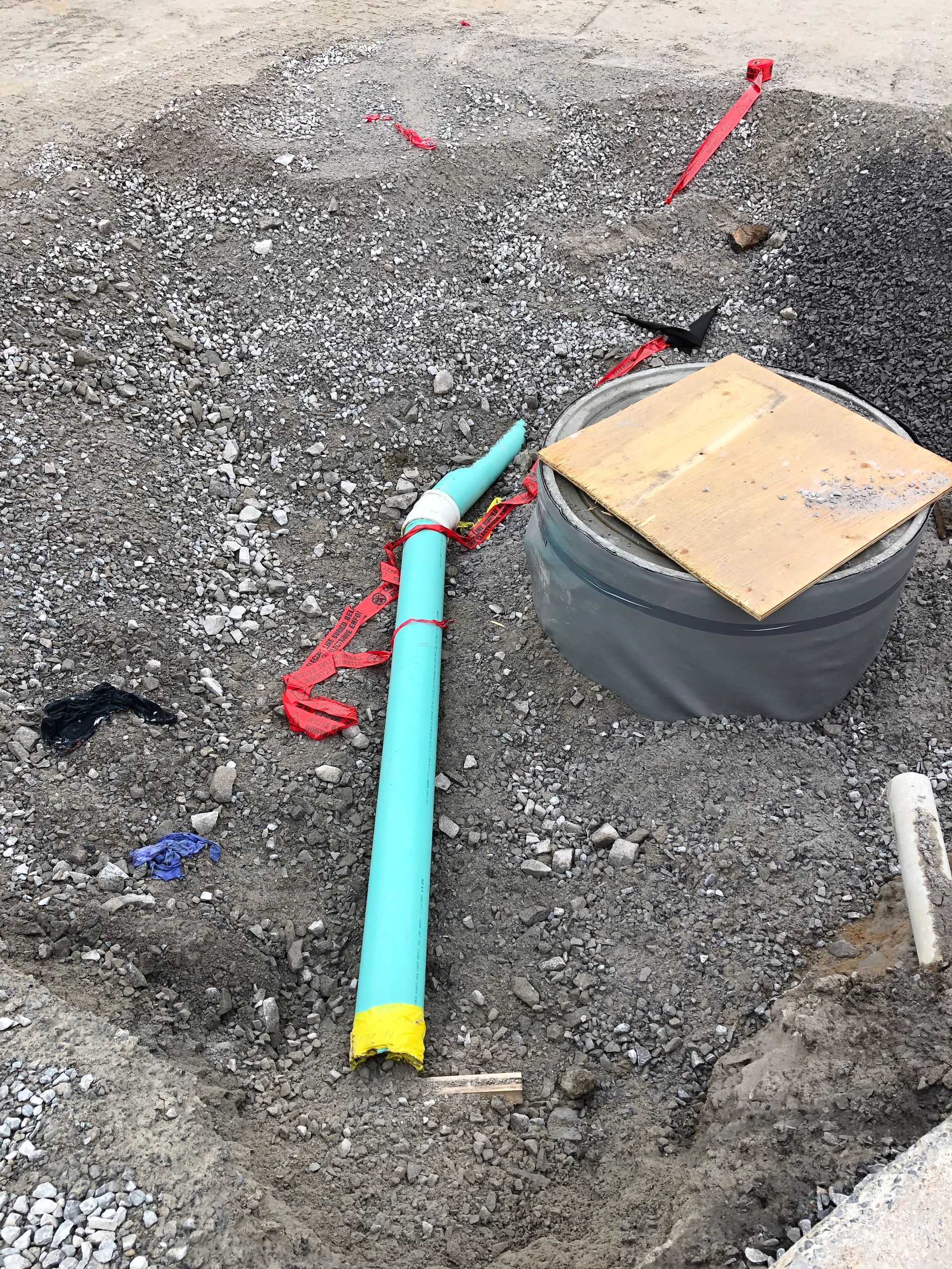 Un tuyau vert repose sur le sol à côté d'un anneau de béton.