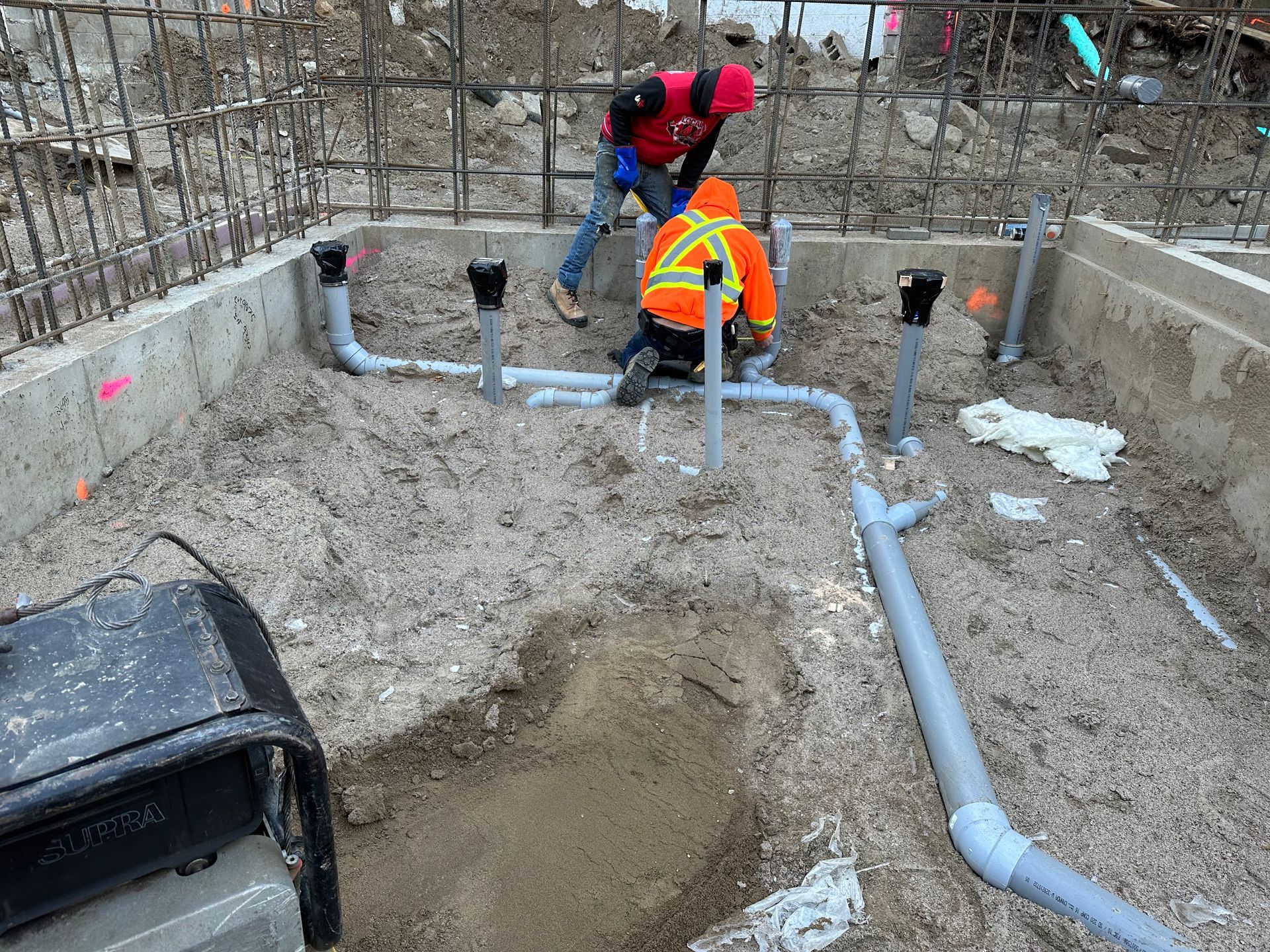 Un groupe d’ouvriers du bâtiment travaille sur des tuyaux enfouis dans la terre.