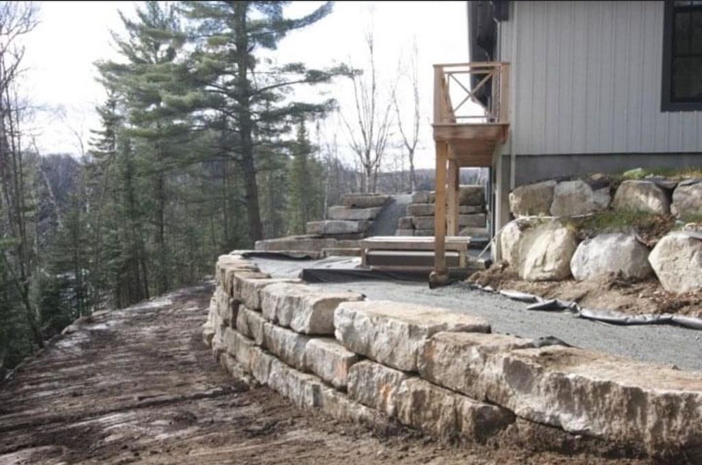 Un mur de pierre est en construction devant une maison