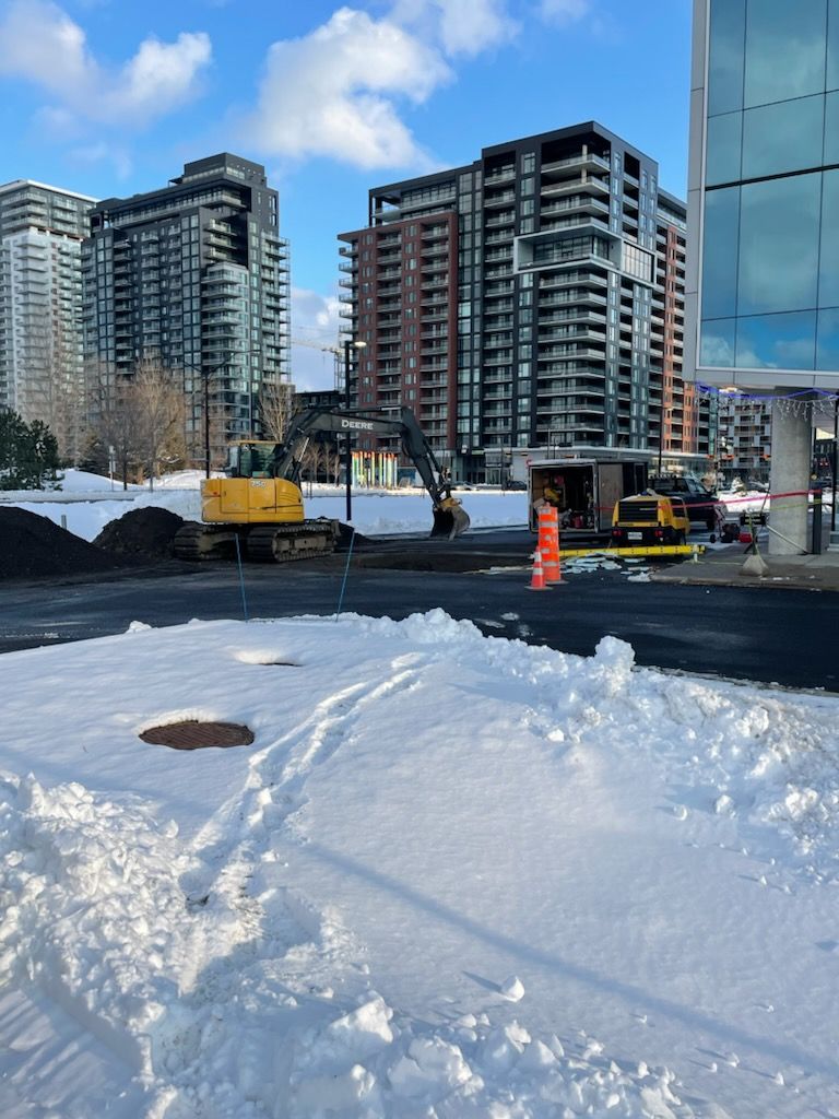 Un chantier de construction avec beaucoup de neige et des bâtiments en arrière-plan