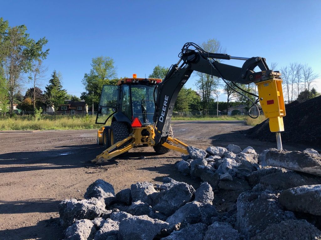 Un bulldozer brise des pierres dans un parking.