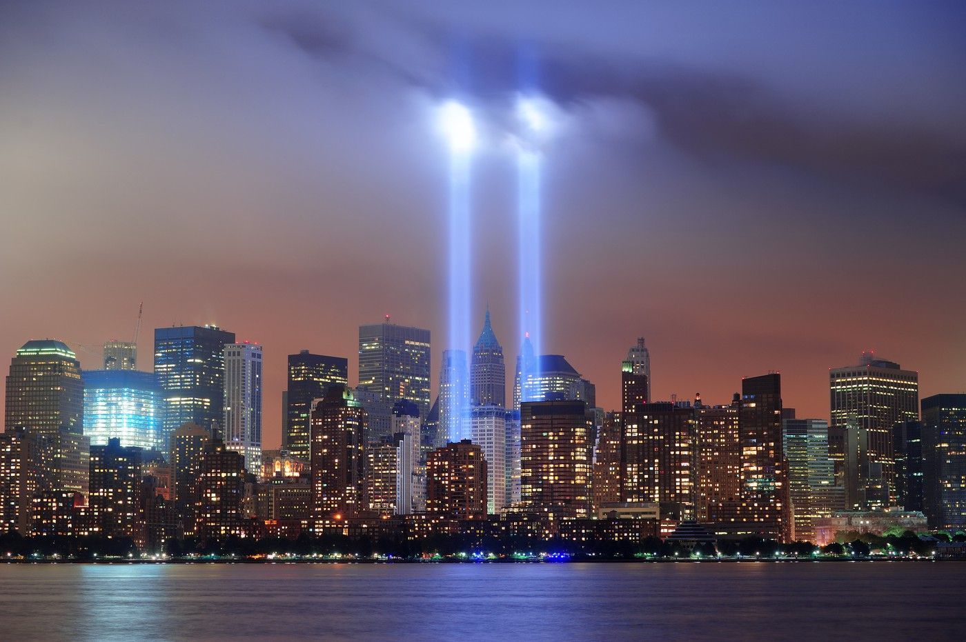 New York City skyline at night with the Twin Towers beams over the water