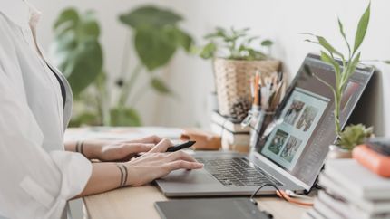 a person sitting at a desk with their laptop