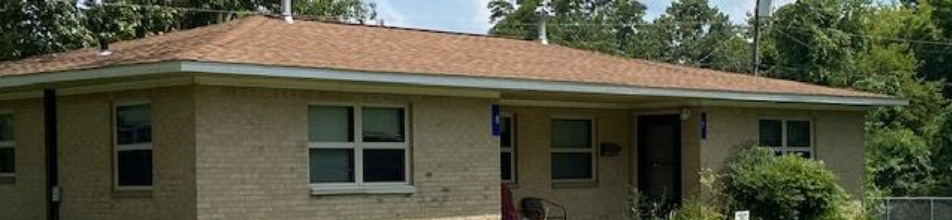 Single-story beige house with red tile roof, front porch, windows, and a mailbox in the yard