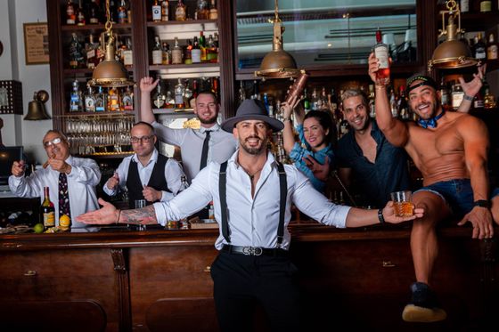 A group of men are posing for a picture in a bar.