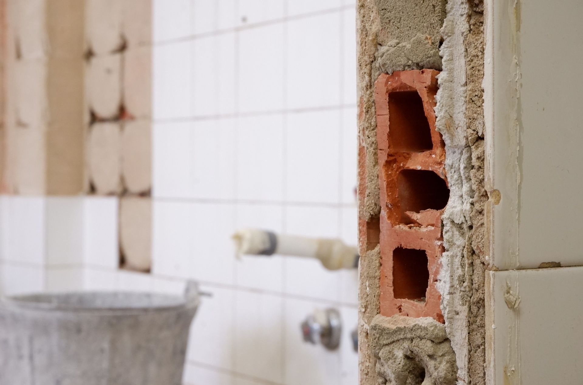 Partially demolished bathroom wall exposing red bricks and tiled interior