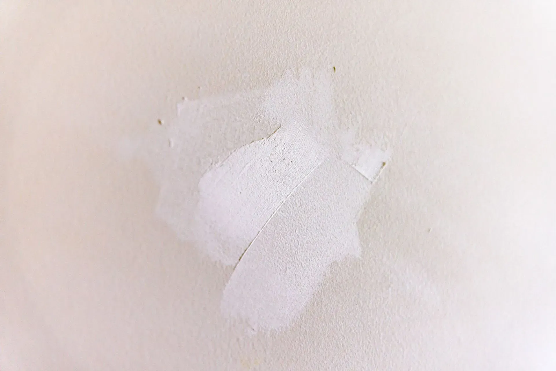 Close-up of a white wall with a rough, peeling paint patch