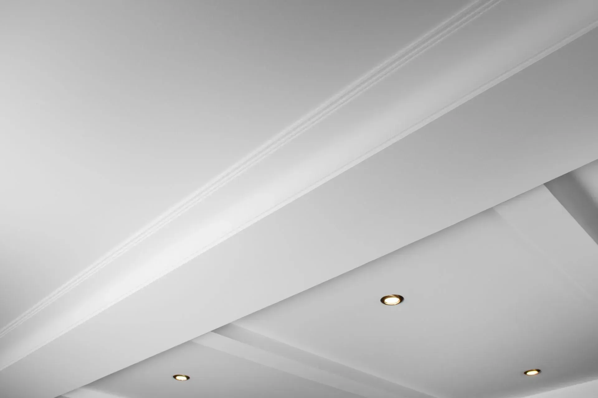 White ceiling with recessed lights and crown molding viewed at an angle