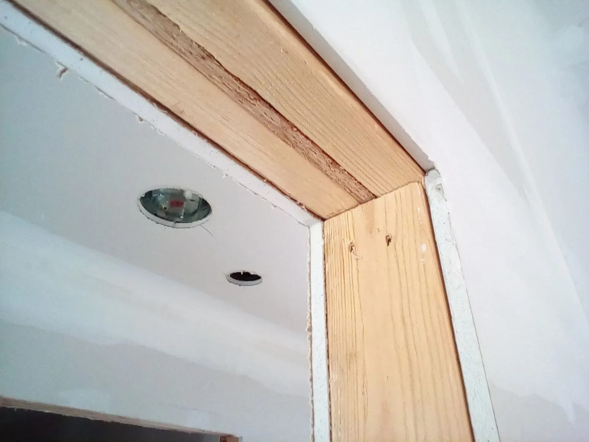 Partially finished door frame with exposed wood trim and ceiling light cutouts