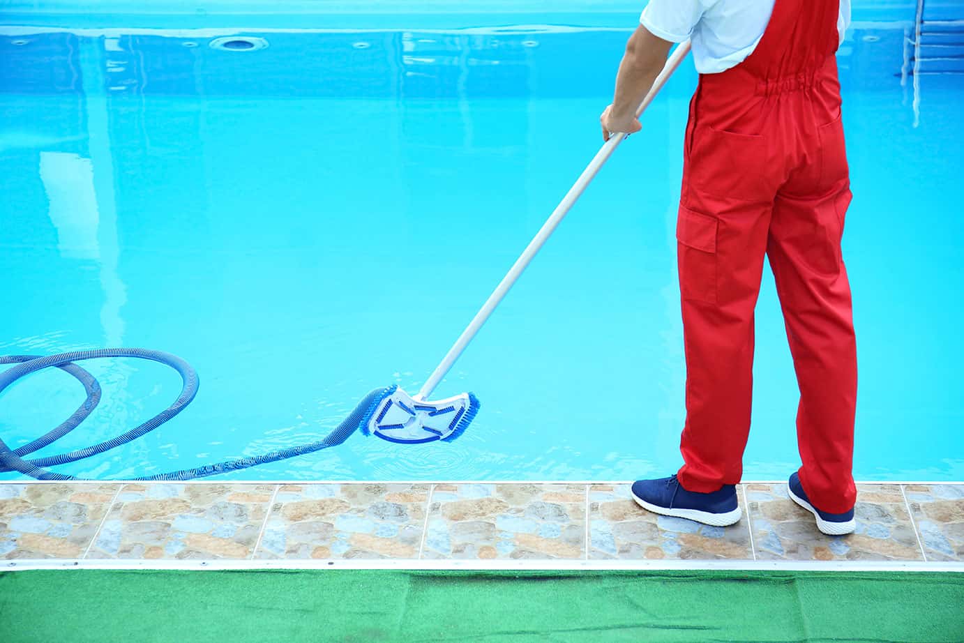 A man operating a pool cleaner, diligently maneuvering the device along the pool's surface to remove debris and maintain its cleanliness.